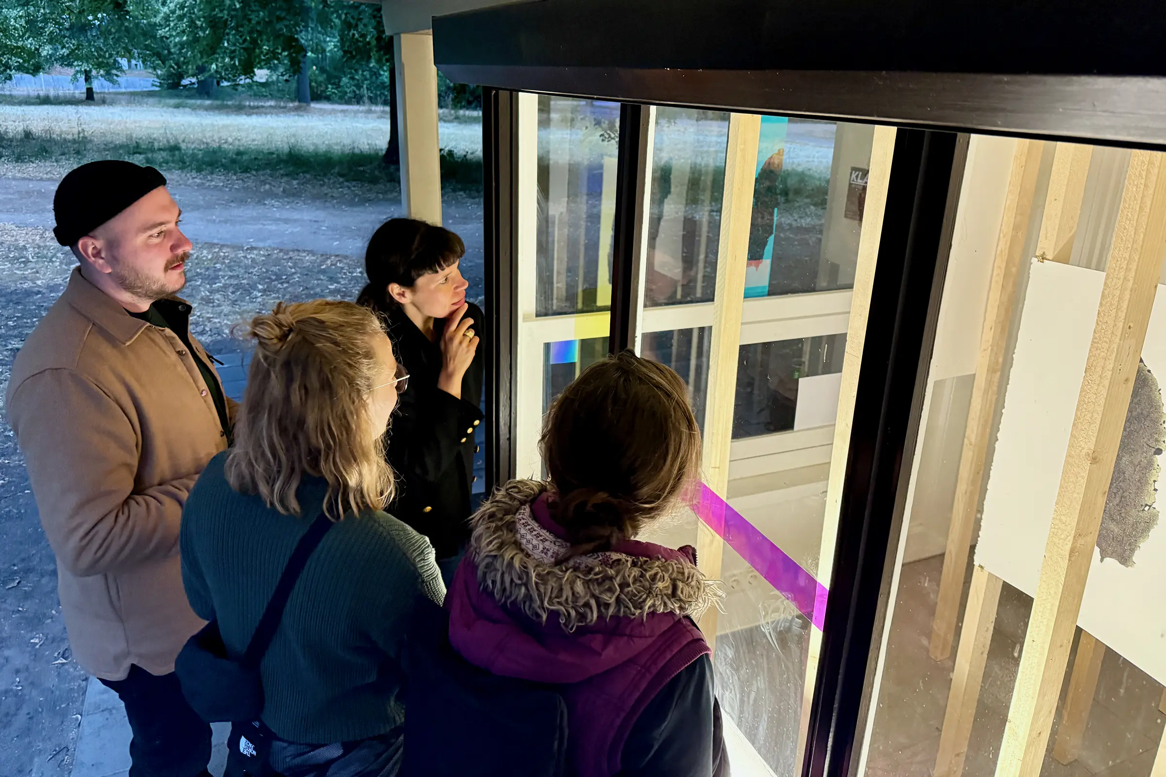 Four guests stand at the window and look inside.